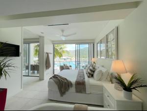 a white bedroom with a bed and a living room at Absolutely Lovely Waterfront Apartment 333 in Nelly Bay