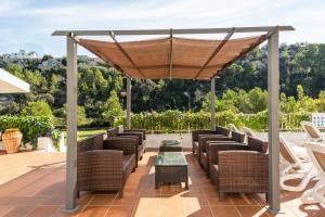 an outdoor patio with wicker chairs and a canopy at Apartamentos alta galdana playa in Cala Galdana