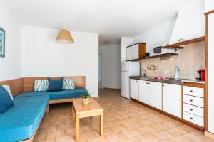 a living room with a blue couch and a kitchen at Apartamentos alta galdana playa in Cala Galdana