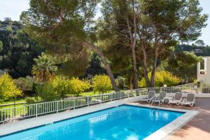 a swimming pool with chairs and trees in a yard at Apartamentos alta galdana playa in Cala Galdana