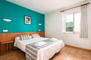 a bedroom with two beds and a blue wall at Apartamentos alta galdana playa in Cala Galdana