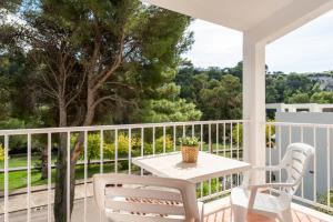a white porch with a table and chairs on it at Apartamentos alta galdana playa in Cala Galdana
