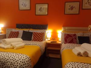 two beds in a room with orange walls at Apartment Sleeps 10 - Pets Parking Ev Charging in Walsall
