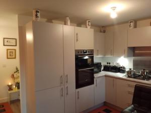 a kitchen with white cabinets and black appliances at Apartment Sleeps 10 - Pets Parking Ev Charging in Walsall