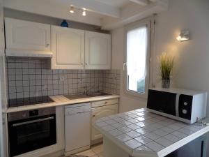 Una cocina con gabinetes blancos y un microondas. en Saint Palais sur Mer - BEL APPARTEMENT 5 min à pied de la PLAGE du BUREAU, en Saint-Palais-sur-Mer