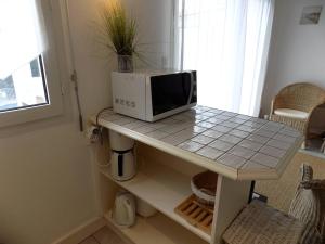 un microondas sentado sobre una mesa en la cocina en Saint Palais sur Mer - BEL APPARTEMENT 5 min à pied de la PLAGE du BUREAU, en Saint-Palais-sur-Mer