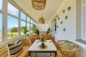 a living room with a table and chairs and windows at Stoep By Ideas Cartel in Kalk Bay