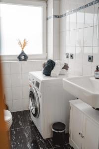 une salle de bain blanche avec une machine à laver et un lavabo dans l'établissement Smart & Stay Living, à Mörlenbach 17 autres photos