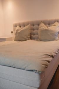 Elle comprend un grand lit avec des draps et des oreillers blancs. dans l'établissement Smart & Stay Living, à Mörlenbach