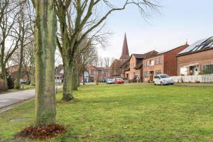 a tree in the grass in a town with a church at Klaus Lafrenz Petersdorf N°2 in Fehmarn