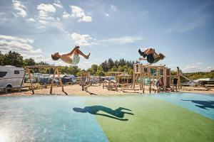 a group of people jumping into a pool at a playground at Bryrup Camping in Bryrup
