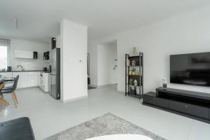 a white living room with a kitchen and a television at Spacious House with Balcony Ideal for Families by Noclegi Renters in Poznań +14 photos