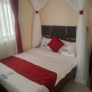 a bed with white sheets and red pillows at Frepego Lakeview Resort in Mbita