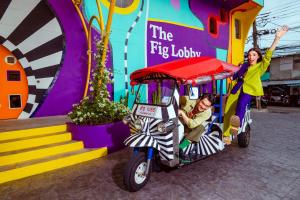 a woman riding a golf cart in front of a building at The Fig Lobby Bangkok in Bangkok