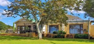 une maison avec un arbre devant dans l'établissement OppiePlaas Country Estate, à Haga-Haga