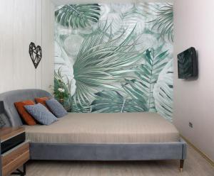 a bed in a room with a mural of a plant at Apartment & Parking "Opera at the corner" in Odesa