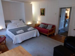 a bedroom with a bed and a red chair at Large Bright Soho Studio flat with Large Terrace in London