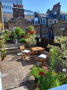a patio with two chairs and a table and some plants at Large Bright Soho Studio flat with Large Terrace in London