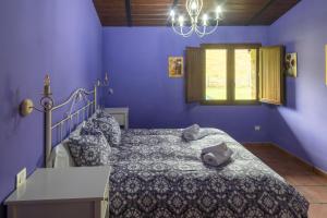 a bedroom with a bed with purple walls and a window at Aitxitxe in Carranza