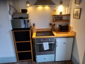 a small kitchen with a stove and a microwave at Large Bright Soho Studio flat with Large Terrace in London