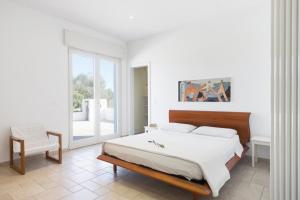 Un dormitorio blanco con una cama y una silla. en Villatrullo Melograno, en Torre Suda 32 fotos más