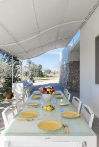 una mesa larga con platos amarillos y flores en ella en Villatrullo Melograno, en Torre Suda