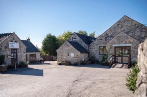 a group of three stone buildings with a driveway at Horton's Hideaway at Ashbourne Heights Holiday Park in Ashbourne