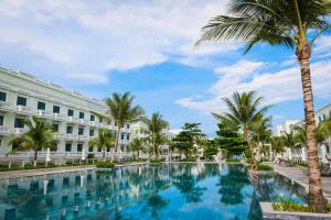 a swimming pool in front of a building with palm trees at Meridian apartment service at Marina Long beach Phu Quoc in Phú Quốc