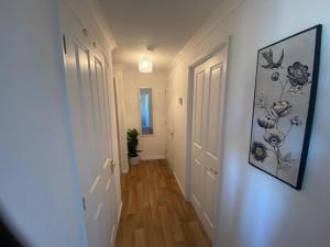 a hallway with a white door and a painting on the wall at Paddock View - Snetterton Norfolk in Norwich