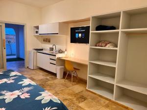 a room with a bed and a desk and a kitchen at Flat's Maravista Beiramar in São Miguel do Gostoso