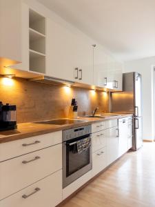 a kitchen with white cabinets and a stove top oven at Wohnen bei Franzi - Tolle Wohnung für 4 Personen in Altötting +11 photos