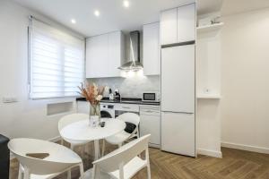 une cuisine avec des placards blancs et une table et des chaises blanches dans l'établissement Urban Tranquility in Madrid with Modern Comforts, à Madrid 18 autres photos