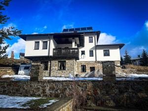 a house with a solar roof on top of a stone wall at Къща за гости МЕЧА СТЪПКА in Gela