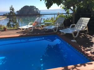 Casa y vista maravillosa, con piscina Coliumo Tomé في تومي: سطح مع كراسي ومسبح
