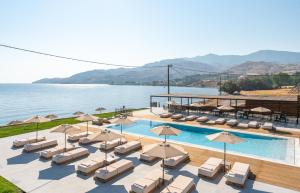 a pool with chairs and umbrellas next to the water at Hotel Angels in Mythimna