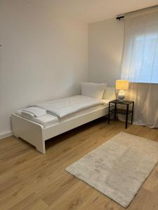 uma cama branca em um quarto com um tapete e uma janela em WW02 - Businessapartment Koblenz em Koblenz