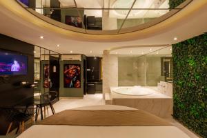 a bathroom with a bed and a tv and a tub at Motel Paradiso - Panambi-RS in Tabapira