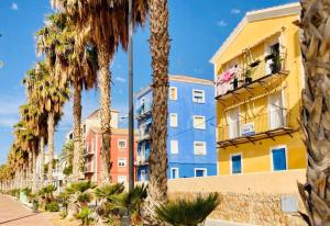 a building with palm trees in front of it at Encantador Apartamento en Primera Línea de Playa in Villajoyosa