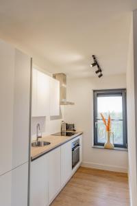 a white kitchen with a sink and a window at Boerderijkamer Ochtendzon in Lutten +6 photos