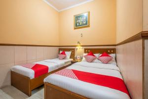 two beds in a room with red and white pillows at Collection O Kebon Jeruk Near Taman Balai Kota in Bandung