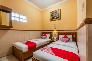a room with two beds with red and white pillows at Collection O Kebon Jeruk Near Taman Balai Kota in Bandung