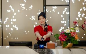 a woman standing next to a table with flowers at d'primahotel PIK Jakarta in Jakarta