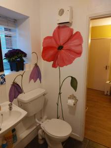 a bathroom with a toilet and a flower on the wall at Cosy 2 bed cottage next to Fota Wildlife Park in Cork