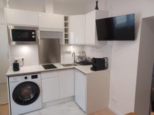 een witte keuken met een wasmachine en een wastafel bij La Demeure du Chevalier in Saint-Cyr-lʼÉcole