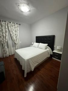 una camera da letto con un letto con lenzuola bianche e una finestra di Playa Isomara a Puerto del Rosario