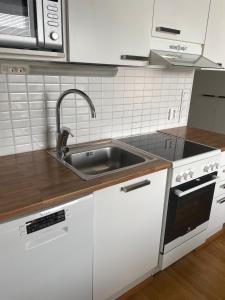 a white kitchen with a sink and a stove at Cozy Top-Floor Studio in Turku - Near City Center in Turku