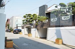 un bâtiment avec des bonsaïs sur le côté d'une rue dans l'établissement Oasita Hostel, à Gwangju
