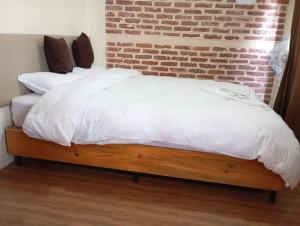a bed with white sheets and a brick wall at Pilachhen Sinpa 1 Bhk in Pātan