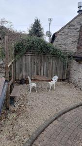 a backyard with two chairs and a wooden fence at Top Floor Malthouse Studio Apartment in Much Wenlock
