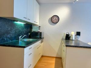 a kitchen with a sink and a clock on the wall at Sonniges Bergblick-Appartement in Damuls
